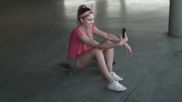 Skate atrakcyjna młoda kobieta biorąc selfie się z jej silny telefon na parkingu - Materiał filmowy, wideo