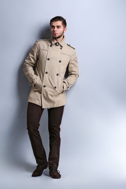 Young man in coat on gray background - Foto, immagini