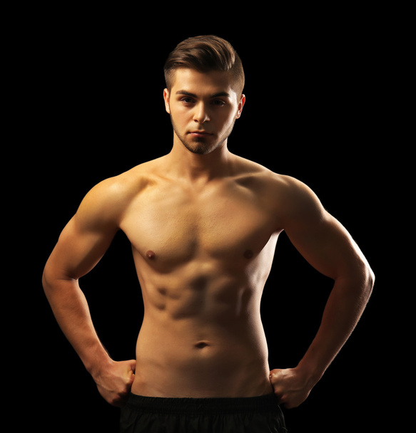 νεαρός άνδρας μυών σε σκούρο φόντο - Φωτογραφία, εικόνα
