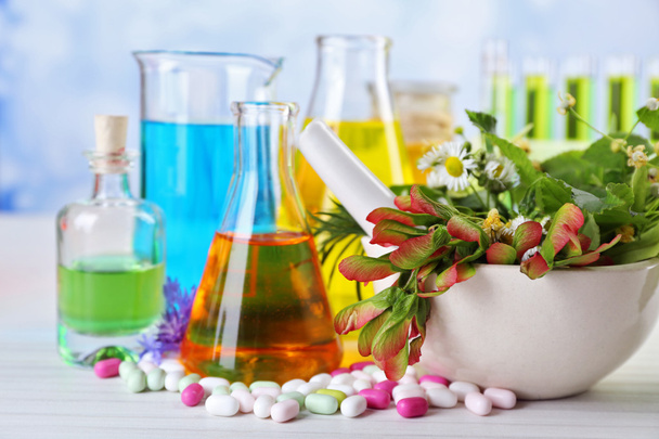 Herbs in mortar, test tubes and pills,  on table, on light background - Φωτογραφία, εικόνα
