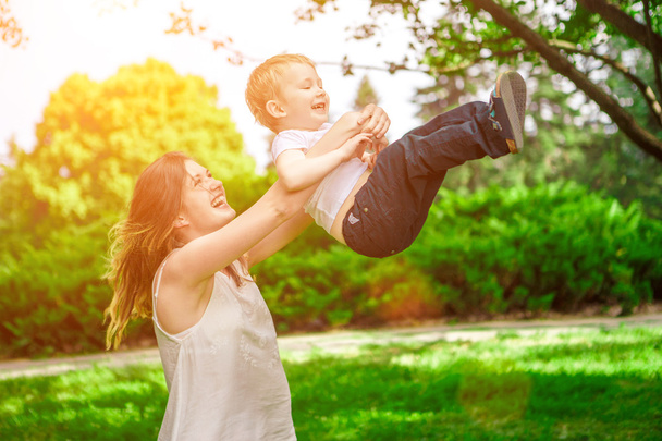 Cute cheerful child with mother play outdoors - Fotoğraf, Görsel