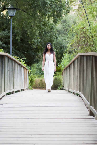 Hermosa mujer en un puente de madera en el parque
 - Foto, Imagen