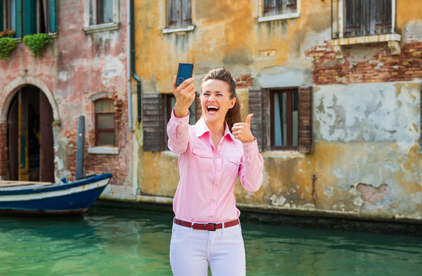 Woman tourist in Venice taking selfie and giving thumbs up - Fotó, kép