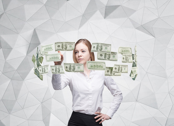 Young lady is controlling cash flow of the dollar notes. Contemporary background. - Foto, Imagen