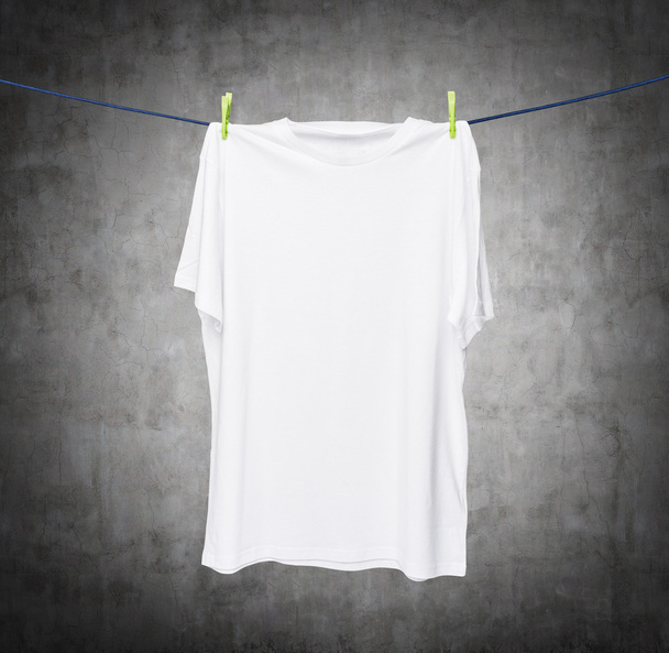Close up van een wit t-shirt op het touw. Concrete achtergrond. - Foto, afbeelding