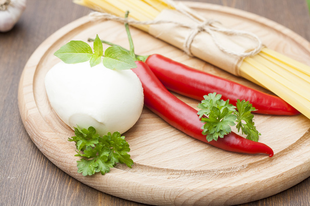 Mozzarella with herbs, noodles, chilli, on a wooden round board, selective focus - Φωτογραφία, εικόνα