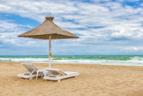 Mustanmeren ranta sateenvarjot, hieno hiekka, viileä vesi ja sininen taivas
 - Valokuva, kuva