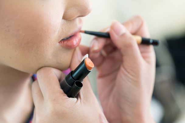 Oranje lippenstift van make-up met cosmetische voor vrouw - Foto, afbeelding