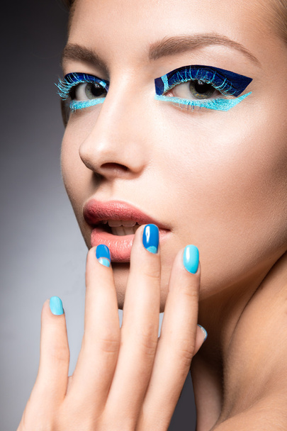 Hermosa chica con brillante maquillaje de moda creativa y esmalte de uñas azul. Arte belleza diseño
.  - Foto, Imagen