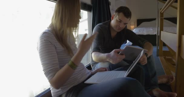 Man and woman talking while using pad and laptop - Filmmaterial, Video