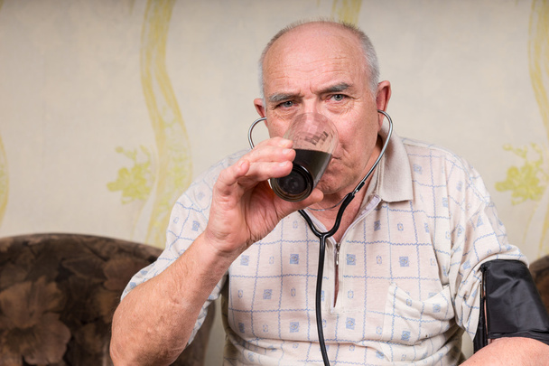 Old Man with Stethoscope Drinking a Glass of Juice - Valokuva, kuva