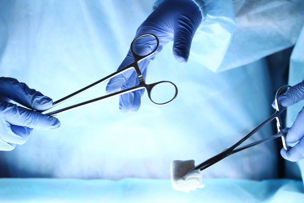 Χειρουργοί τα χέρια κρατώντας και περνώντας χειρουργικά μέσο σε άλλο  - Φωτογραφία, εικόνα
