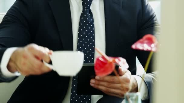 Biznesmen za pomocą cyfrowego tabletu i picia kawy - Materiał filmowy, wideo