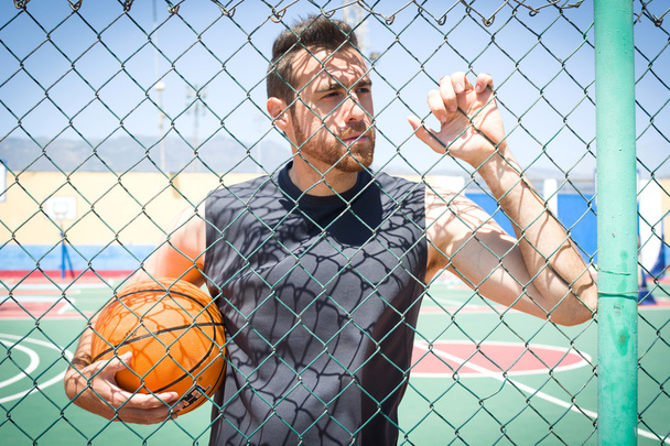 giovane uomo con una pallacanestro dietro una recinzione
 - Foto, immagini