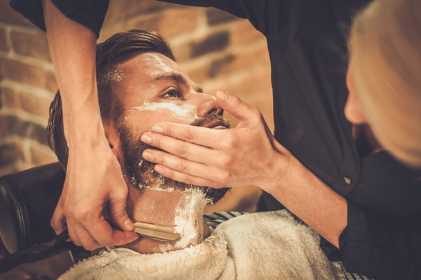 Cliente durante el afeitado de barba en la peluquería - Foto, imagen