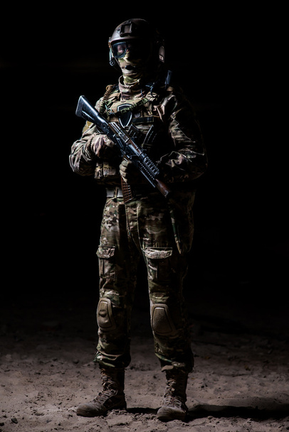 Στρατιώτης σε καμουφλάζ με ένα τουφέκι στέκεται σε μια διμοιρία και ρολόγια - Φωτογραφία, εικόνα