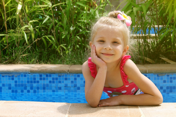 Girl in the pool with one hand near cheek - Foto, afbeelding