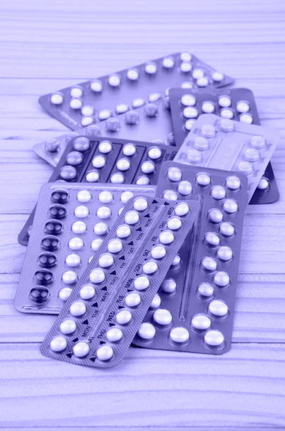 Orális fogamzásgátló tabletta csíkok a fenyő fa asztal. - Fotó, kép