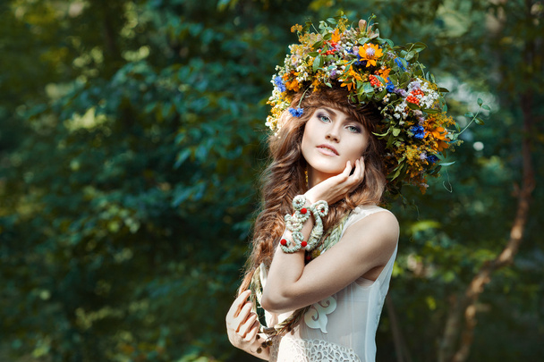 Όμορφη κοπέλα με στεφάνι στο κεφάλι του πεδίου λουλούδια. - Φωτογραφία, εικόνα