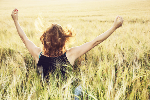 Jovem mulher acenando as mãos para o sol no campo pelo verão
 - Foto, Imagem
