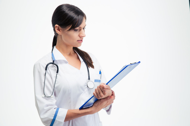 Beautiful medical doctor reading notes on clipboard  - Фото, зображення