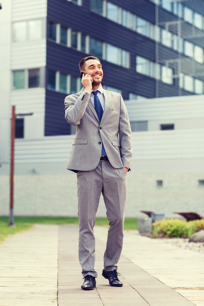 smiling businessman with smartphone outdoors - Fotó, kép