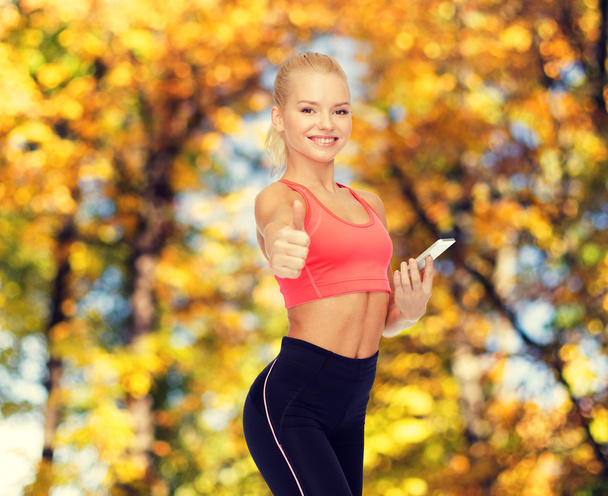 smiling sporty woman with smartphone - Fotografie, Obrázek