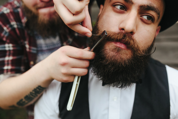 barbero afeita a un hombre barbudo
 - Foto, imagen