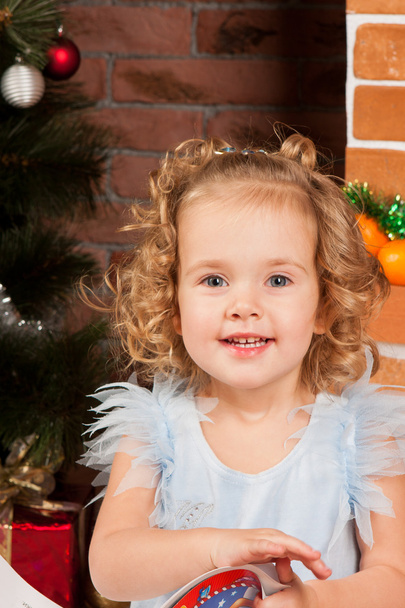 Little girl sitting near Christmas tree - Фото, зображення