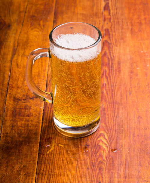 Mug of beer on wooden background - Фото, изображение