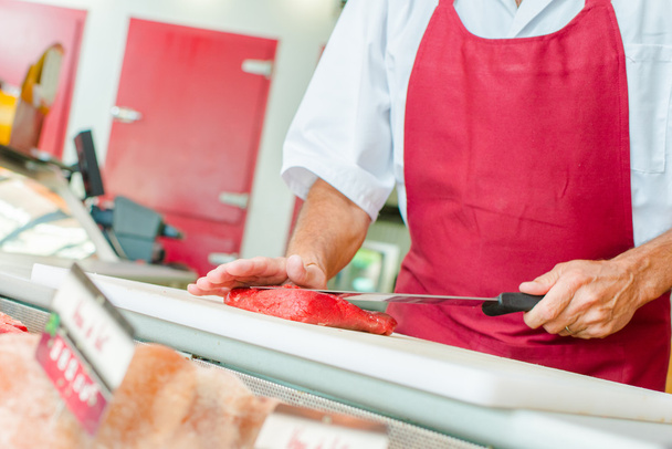 Butcher preparing a cut of beef in his shop - Photo, image