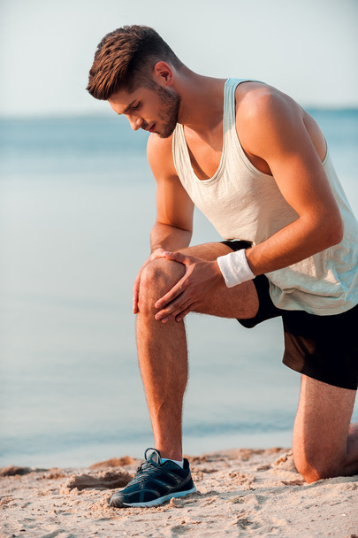 muscular man massaging knee before running - Fotografie, Obrázek
