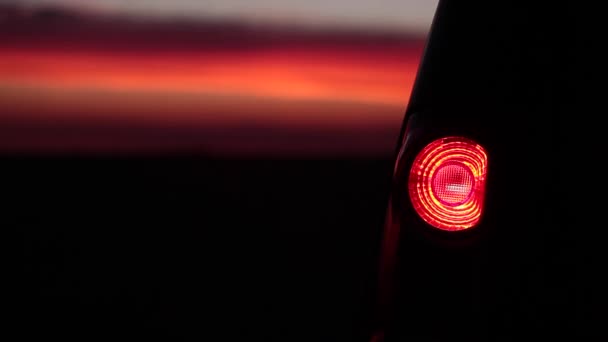 Villogó autó vissza a fény a naplementében - Felvétel, videó
