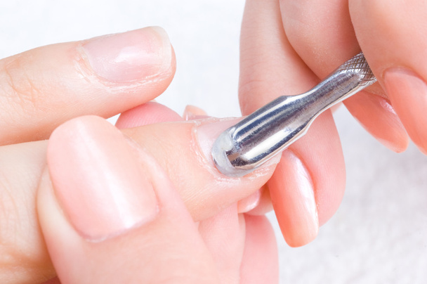 Maniküre anwenden - Nagelhaut mit speziellem Istrument reinigen - Foto, Bild