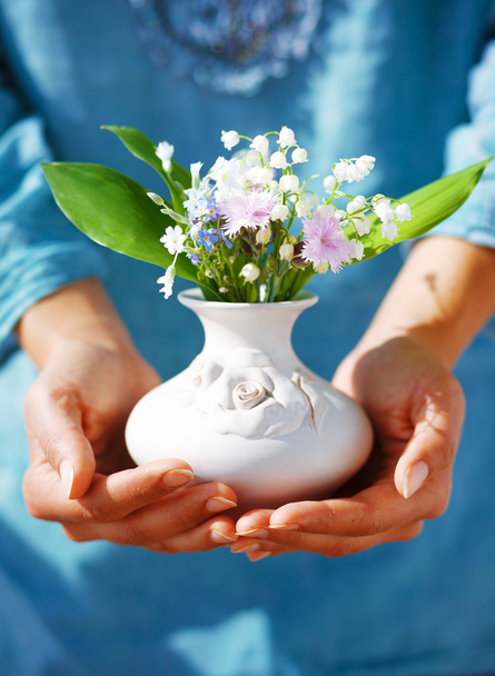 Woman holding bouquet of flower in vase. Blue clothing background - Photo, Image