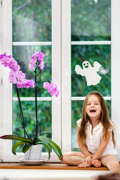 Linda niña con flor sentada en el alféizar de la ventana de pvc nuevo wi
 - Foto, imagen