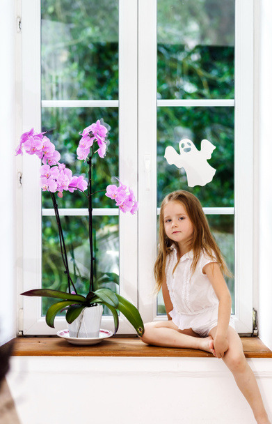 Carino bambina con fiore seduto sul davanzale della finestra di nuovo pvc wi
 - Foto, immagini