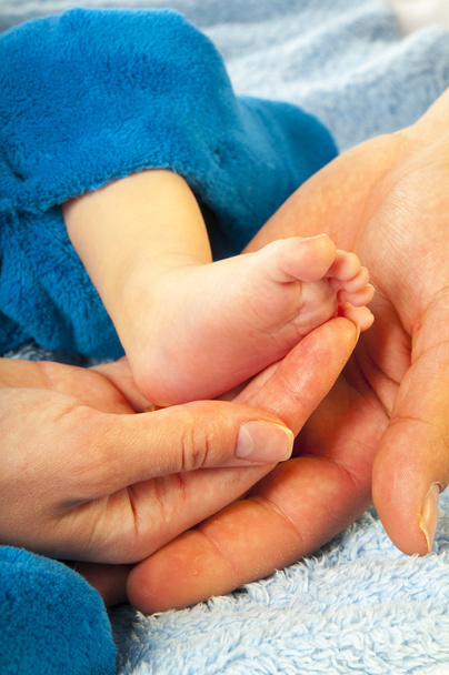 Perna de bebê nas mãos dos pais
 - Fotografia, imagem