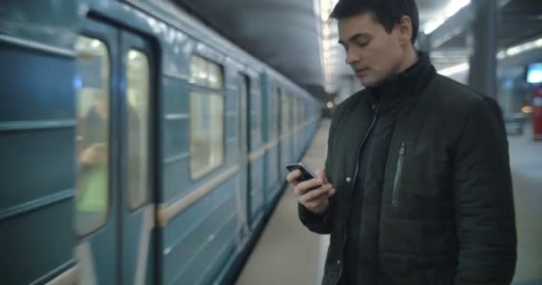 Mann tippt SMS auf U-Bahn-Bahnsteig - Filmmaterial, Video