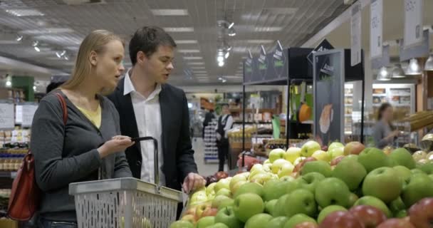 Nuoret valitsevat omenoita supermarketista - Materiaali, video