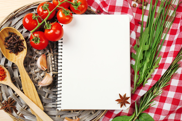 Open recipe book with fresh herbs, tomatoes and spices on wooden background - Foto, imagen