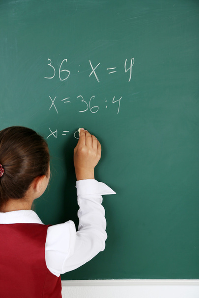 Beautiful little girl writes on blackboard in classroom - Foto, Imagem