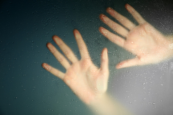 Mano femenina detrás de vidrio húmedo, primer plano
 - Foto, imagen