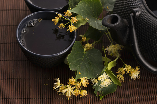 teapot and cup with linden tea and flowers - Photo, Image