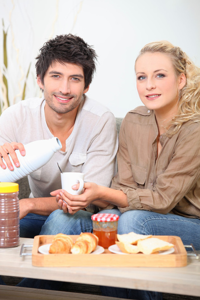 Couple eating breakfast on a sofa - Photo, Image