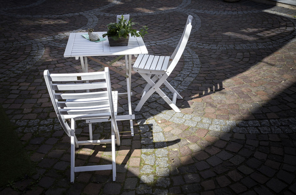 white garden chairs and table in a shopping street - 写真・画像