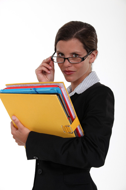 Secretary holding a binder and peering over her glasses - Foto, afbeelding
