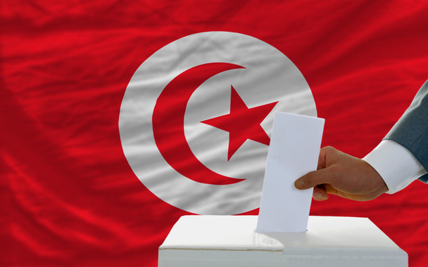 άνθρωπος ψηφοφορία στις εκλογές στην Τυνησία μπροστά από την σημαία - Φωτογραφία, εικόνα