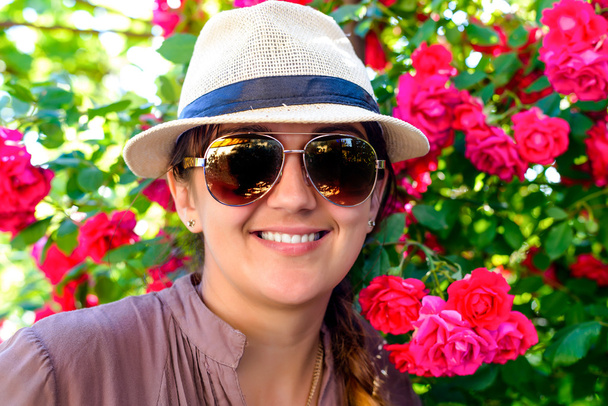 Hymyilevä nainen vastaan kaunis punainen kukka kasvi
 - Valokuva, kuva
