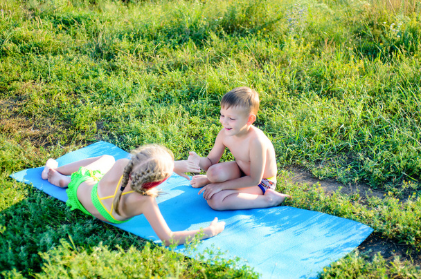 Feliz lindo niños acurrucarse en la estera en la hierba
 - Foto, Imagen